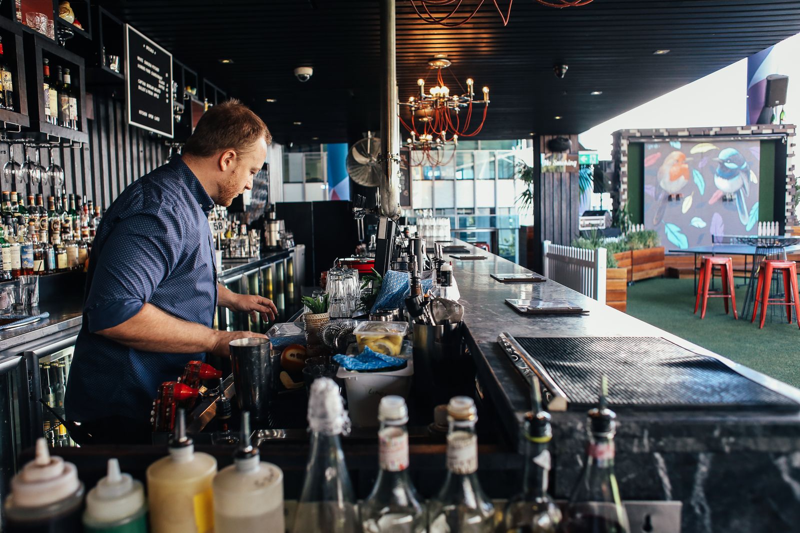 A bartender working the well behind a service bar, the station a bar cleaning checklist has to cover every night